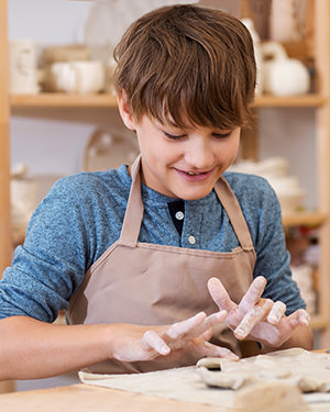 teenager boy works with clay makes ceramic plate in clay