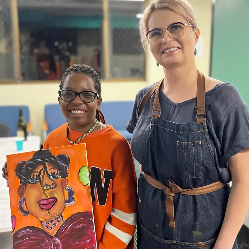 Art teacher and young girl holding a portrait painting
