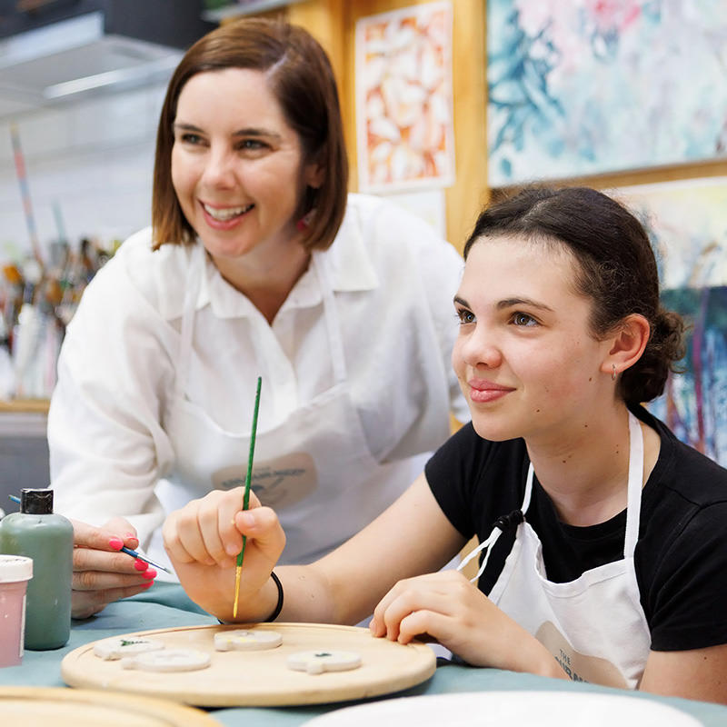 Art workshop with teen girl painting and teacher helping