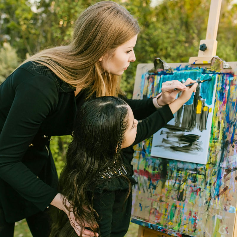 woman and small girl painting at easle