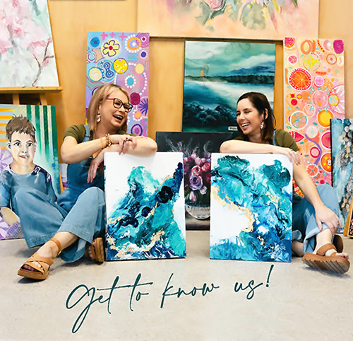 Korryn Swindail Hill and Christina Esdaile sitting on floor among paintings
