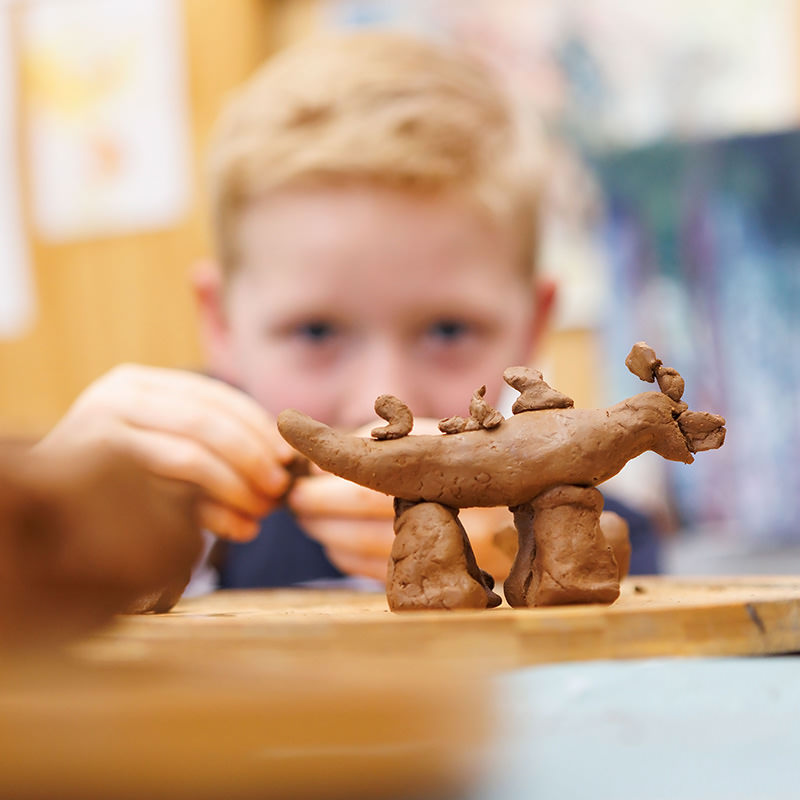 Boy making a clay animal.