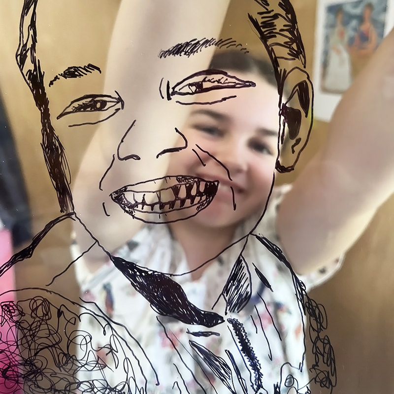 Self portrait of girls face on clear perspex in black ink.