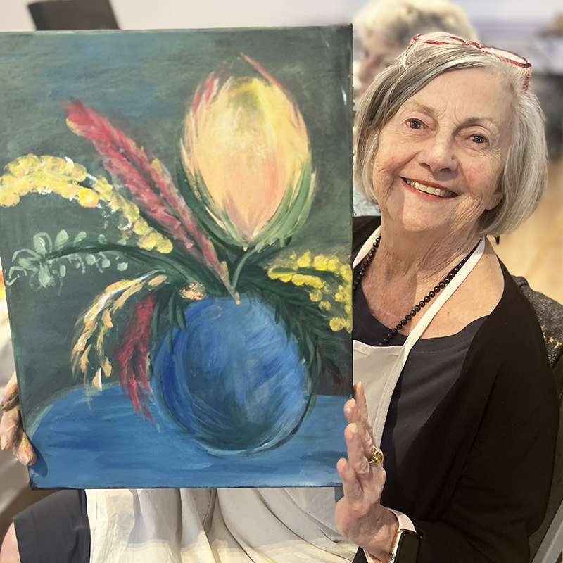 Happy mature woman holding painting of flowers