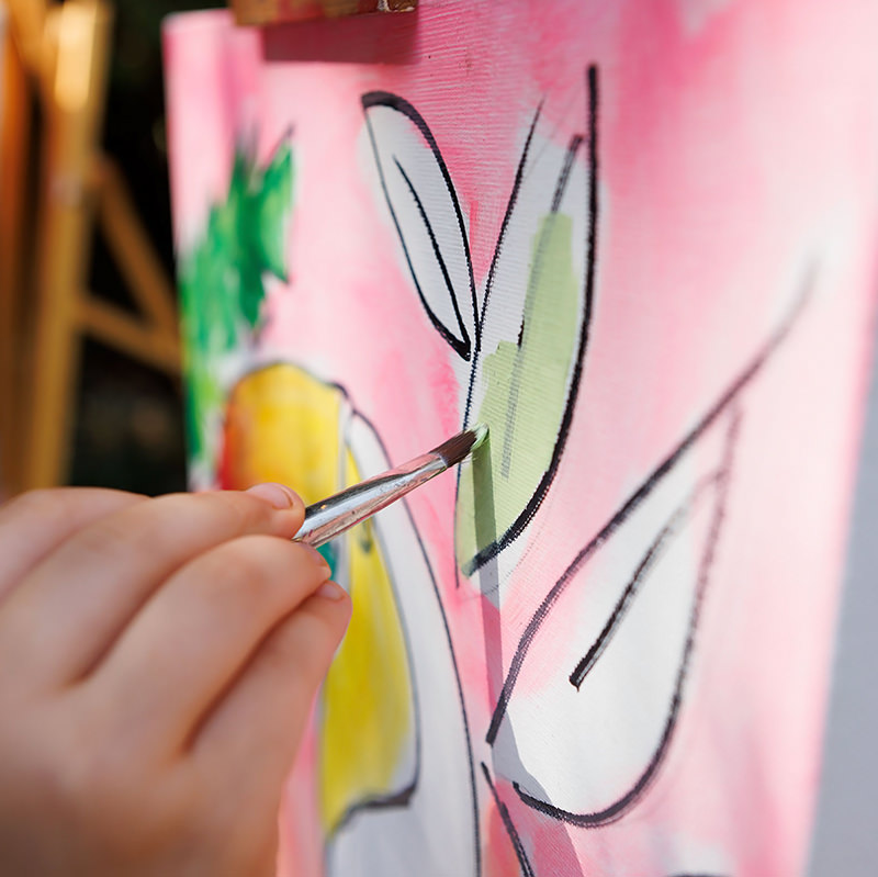 close up of paint brush and canvas painting a leaf