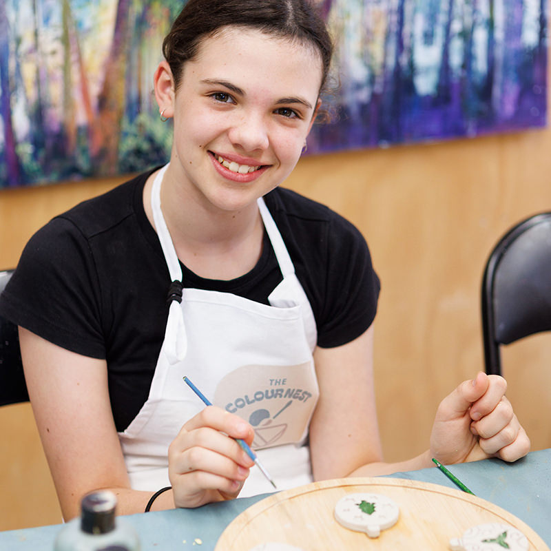 beautiful teenage girl in art class painting xmas tree decoration.